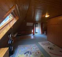 An attic room in a family house with wooden paneling and carpets.