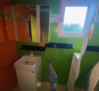 A colorful bathroom in a family house with a sink and a mirror.