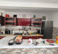 A kitchen in a 2-room apartment with furnishings, red cabinets, and a marble countertop.
