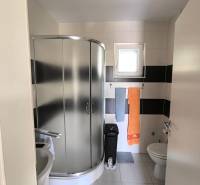 Compact bathroom with a shower, sink, and toilet in a 2-room apartment.