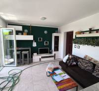 Living room in a two-room apartment with a dark sofa, decorations, and open glass doors.