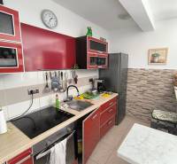 Kitchen in a 2-room apartment with red cabinets, a cooktop, and a stainless steel refrigerator.