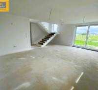 A spacious living room in a 5 or more bedroom apartment with large windows and a staircase.