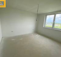A view into an empty room with a window, part of a 5 or more room apartment.