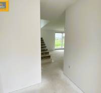 A staircase leading to a bright room in a 5 or more bedroom apartment with a view of greenery.