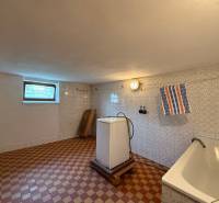 Laundry room in a family house with a bathtub, washing machine, and window.