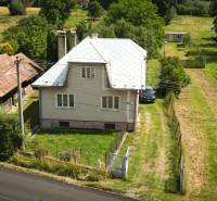 Family house in Konská with a grassy garden, access road, and surrounding nature.
