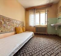 A room with a couch, carpet, window, and sink in a family house.