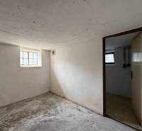 Basement room in a family house with simple interior design, concrete floor, small window.