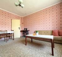 In the living room of a family house with pink wallpaper, an old sewing machine, and furniture.