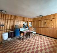 Interior with wooden walls, tiles, a chair, and a table in a family house.