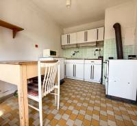 A kitchen in a family house with retro equipment, ceramic tiles, and old furniture.