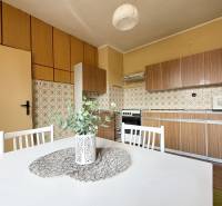 A kitchen in a family house with retro tiles, a kitchen unit, and a white table with a plant.