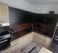 A kitchen in a studio apartment with wooden cabinets and modern appliances.