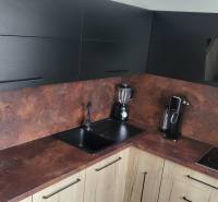 A kitchen in a studio apartment with modern appliances and black cabinets.