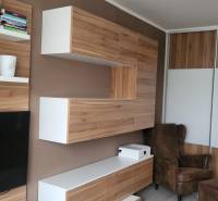 Interior of a 1-room apartment with wooden furniture, a television, and shelves with books.