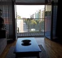 Living room of a two-room apartment with a view of the balcony and city skyline.