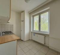 A kitchen with a window and a radiator in a 2-room apartment, light tiles and basic equipment.