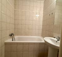 A bathroom with a bathtub and a sink in a 2-room apartment with ceramic tiles.