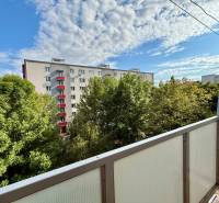 A view from the balcony surrounded by trees and a view of the apartment building on Špačinská Street in Trnava.