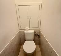 A toilet with a cabinet in a 2-room apartment, white tiles and floor tiles.