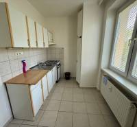 A kitchen with white cabinets and a window in a 2-room apartment.
