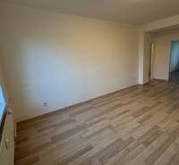 Interior of a 2-room apartment with wooden flooring and white walls.