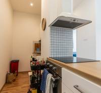 A kitchen in a 2-room apartment with an oven, a hood, and a wooden floor.