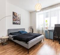 Bedroom in a 2-room apartment with a bed, a desk, houseplants, and wall decorations.