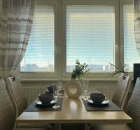 Dining table with placemats, four chairs, and a view of the city from a 2-room apartment.