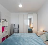 A bedroom with a bed, wardrobe, dresser, and television in a two-room apartment.