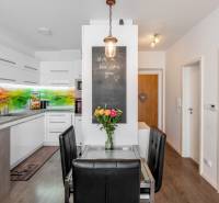 A kitchen in a 2-room apartment with a colored glass panel and a glass table with a vase of flowers.