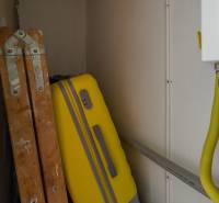 A ladder and a yellow suitcase stored in the utility room of a two-room apartment.