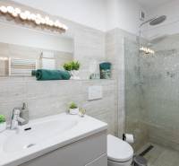 Bathroom in a 2-room apartment with a shower and a sink, furnished in soft colors.