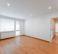A spacious room with a wooden floor and a large window in a 3-room apartment.