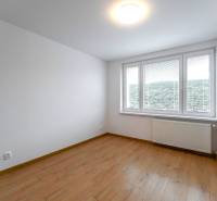 A room with a large window and wooden floor in a 3-room apartment.