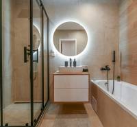 A bathroom with a bathtub, shower corner, and round mirror in a 3-room apartment.
