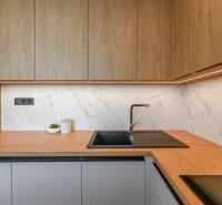 A kitchen in a 3-room apartment with wooden cabinets, a sink, and wine on the countertop.