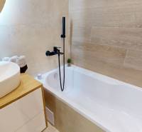 A bathroom with a bathtub, sink, and wooden paneling in a 3-room apartment.