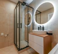 A bathroom in a 3-room apartment with a modern shower and an illuminated mirror.