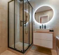 Elegant bathroom with a walk-in shower, round mirror, and sink in a 3-room apartment.