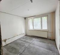 A room under renovation with an empty floor and a large window in a 2-room apartment.