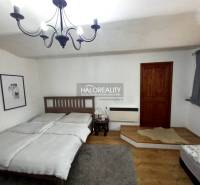 A bedroom with a wooden bed, chandelier, and paintings in a family house.