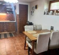 A kitchen in a family house with wooden furniture, brick cladding, and a dining table.