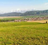 View of agricultural and forest land near Hranovnica with mountains in the background.