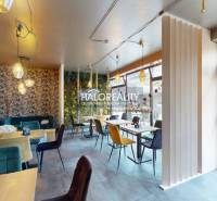 A colorful interior of a gastro space with patterned wallpaper, comfortable chairs, and tables.