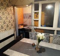 Dining room in a family house with a floral chair, tiled stove, and decorative elements.