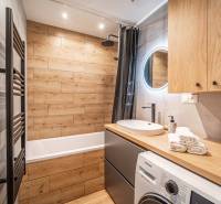 A simple bathroom in a 3-room apartment with wooden details and a washing machine.