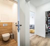 A toilet in a 3-room apartment with wooden paneling and a wardrobe for clothes.