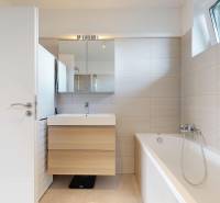 A bathroom in a 3-room apartment with a bathtub, a mirror, and a sink on a cabinet.